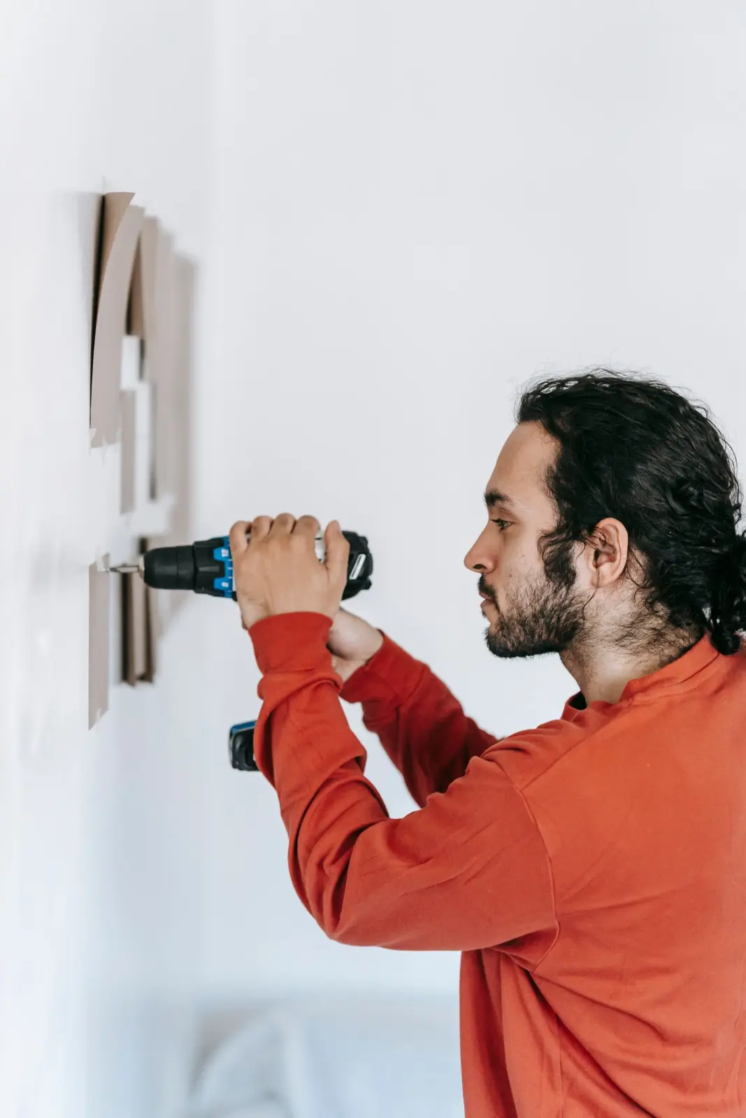 An installer drilling a fitting into a white wall