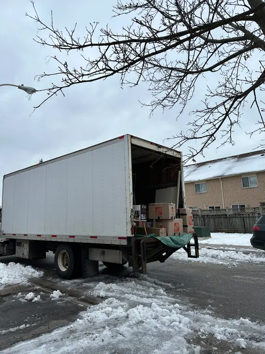An unbranded moving truck parked outside a home on a snowy driveway