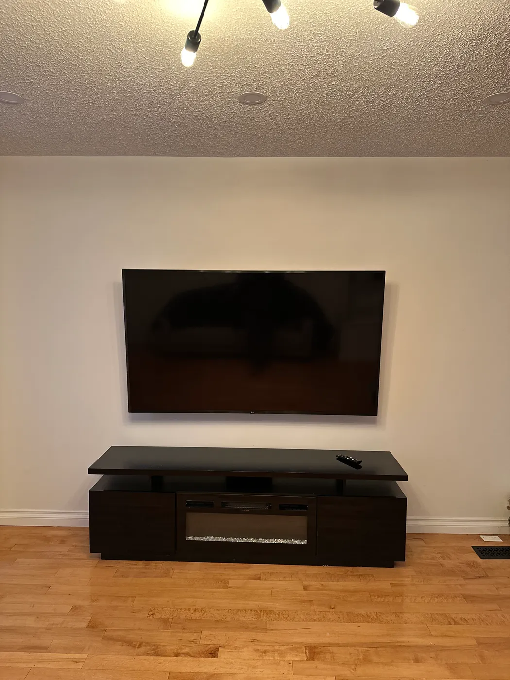 A wall-mounted television above a dark media console in a living room