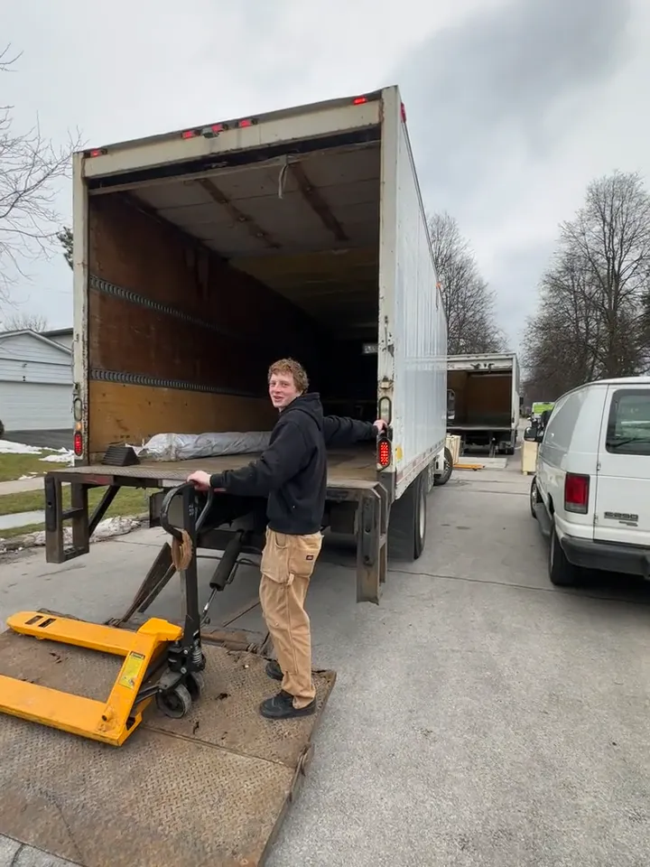 An Optimum crew member beside the open moving truck and a pallet jack