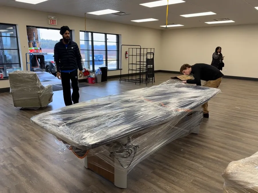 The moving crew wrapping large office furniture before transport